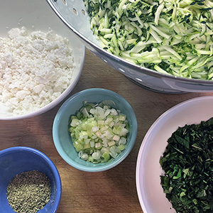 A photo with overhead view of ingredients Joy has prepared to make kolokithokeftedes (Greek zucchini fritters)